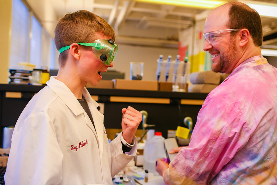 Student and professor smiling in the lab