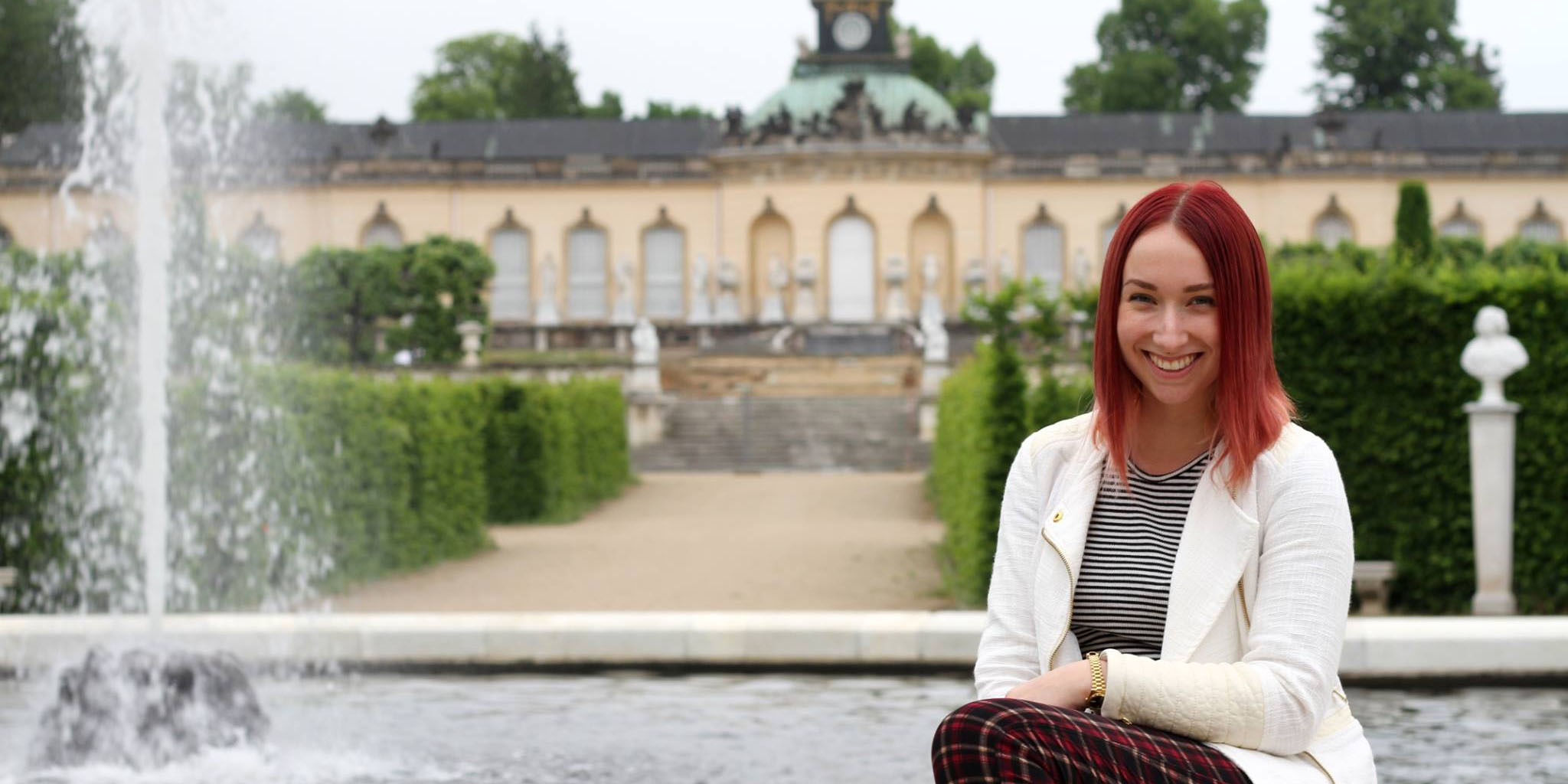 Brieanah Gouveia smiles for a photo next to a palace garden fountain