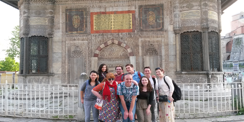 Students and professors pose for photo in front of a historical site in Turkey