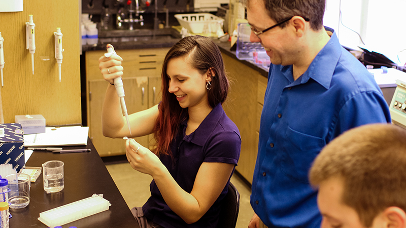 Rebecca Hudon conducts research in a biology laboratory as Professor Chris Lassiter looks on.