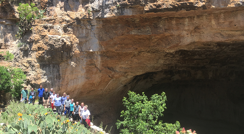students at the mouth of a cave