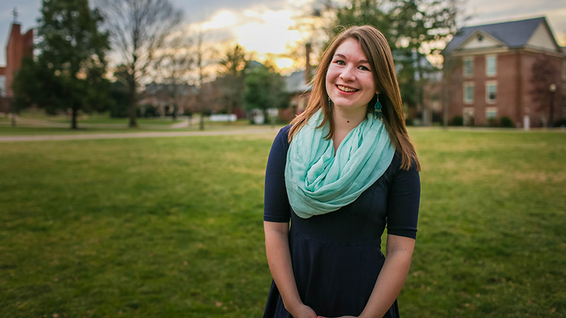 Savannah Scott '17 portrait shot on the back quad in a black dress with a green scarf.