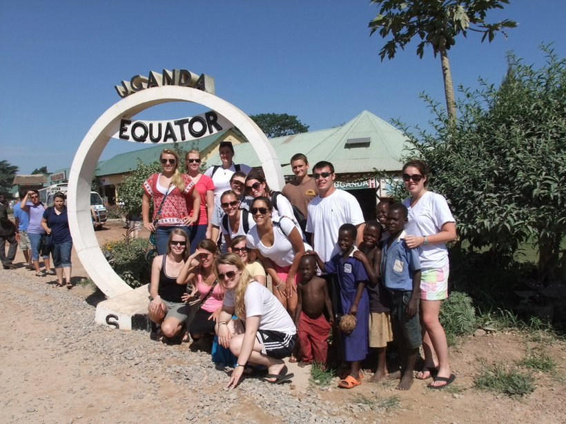 Students posing by the sign signifying where the equator is