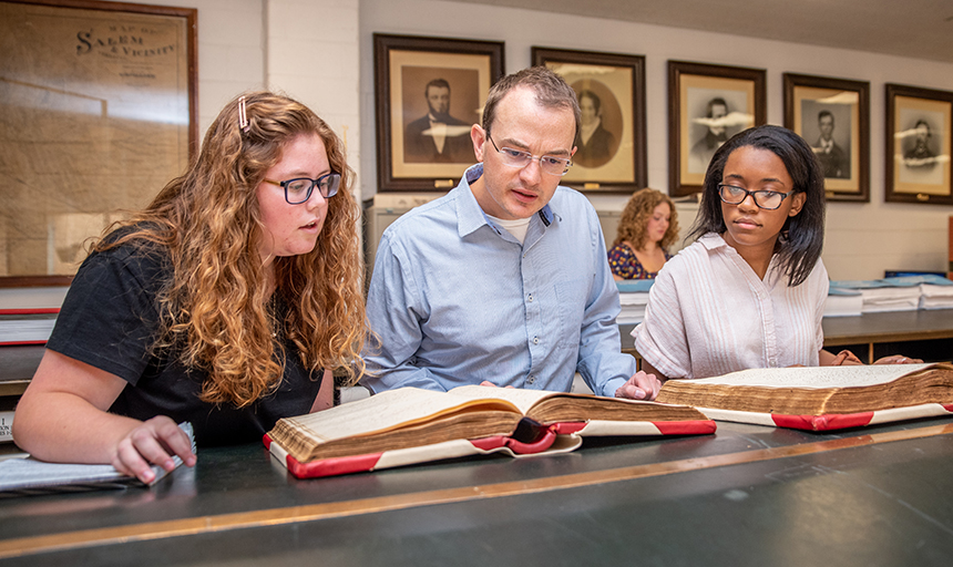 students and professor looking at historical records in the county archive room