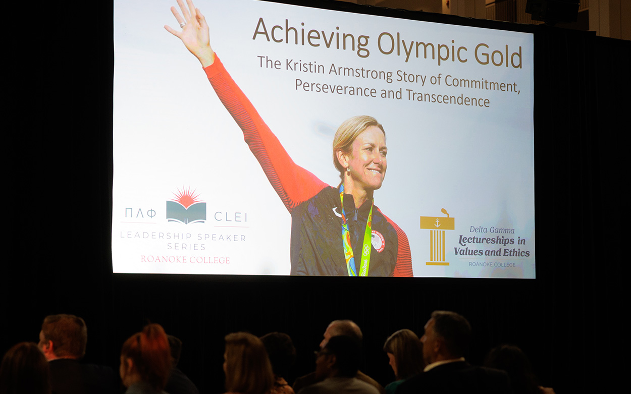 Close-up of slide projected on a large screen showing the name of the event and a picture of Kristin Armstrong with her arm raised in triumph