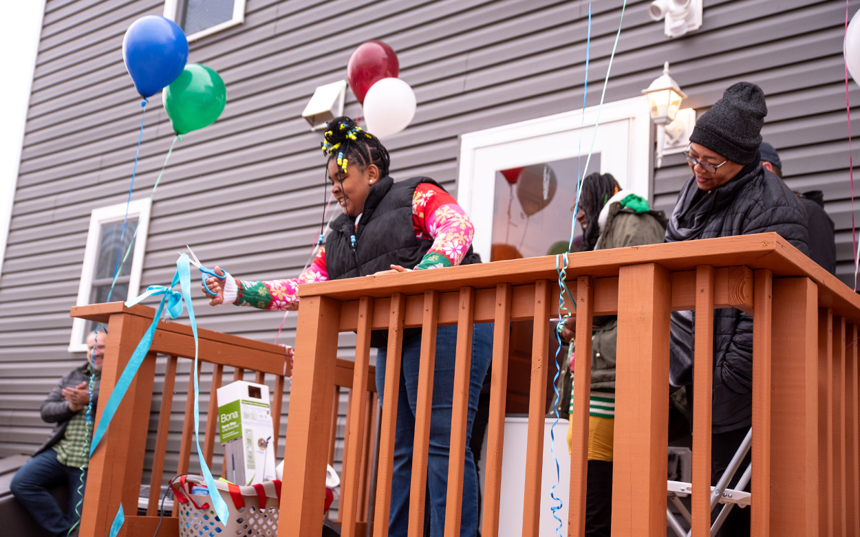 Keshia Jones' daughter leans over to cut a ribbon draped across the porch of their new home.