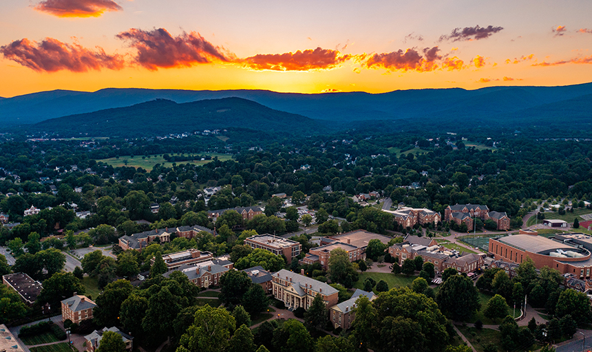 Orange and yellow sunset over the mountains with view of campus in foreground.