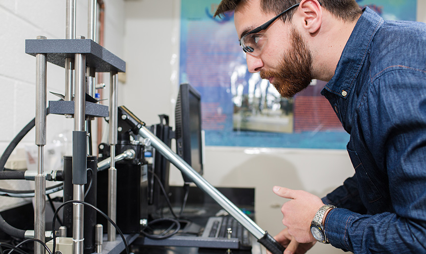 An engineering student works with equipment in a classroom lab