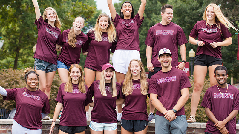 A large group of students that look excited and all wearing matching maroon shirts