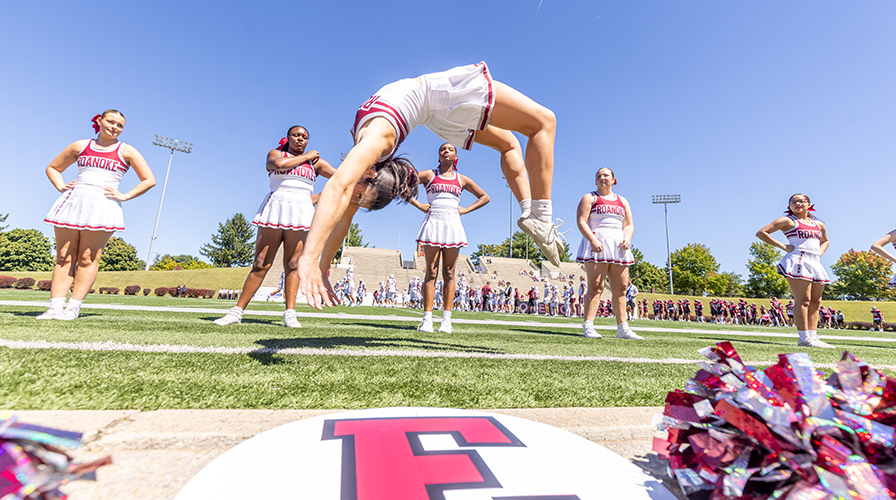 cheerleader doing a flip at a football game