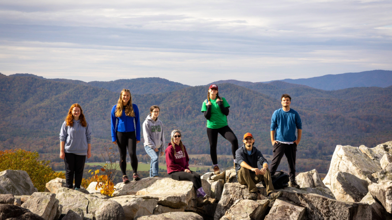 Outdoor Adventures/IMG_2734.jpg Students smiling for a photo on a hike with a mountain view in the background