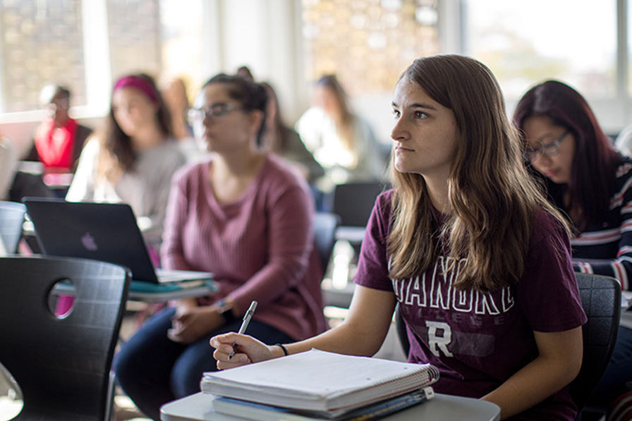 A student in a Roanoke t-shirt listens to a lesson in a classroom