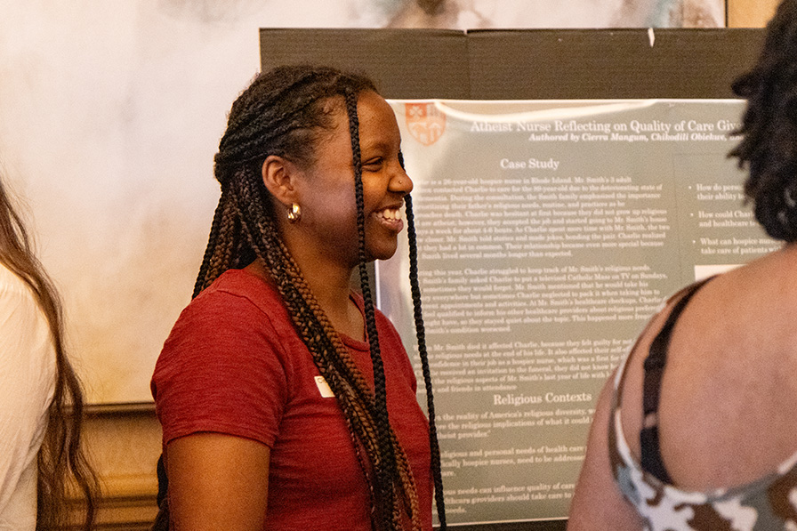 A student smiles while sharing her research during a poster presentation