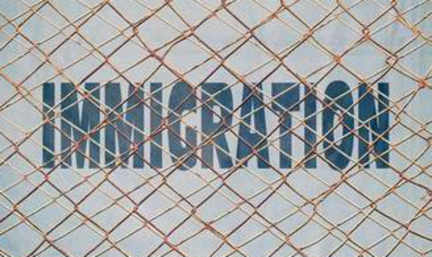 Immigration words behind chain link fence