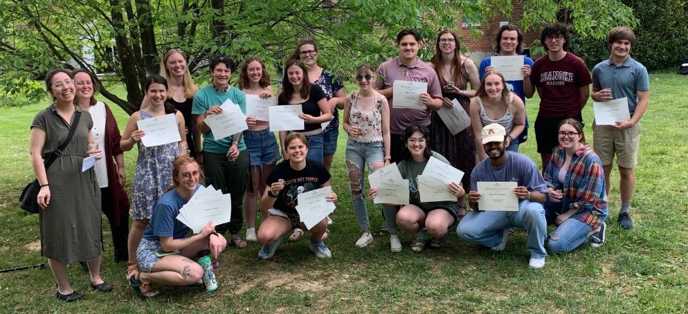 students and faculty standing under a tree