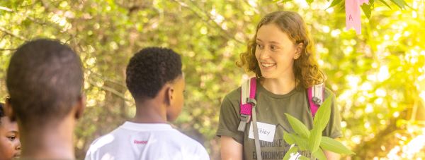 college student talking to children in the woods