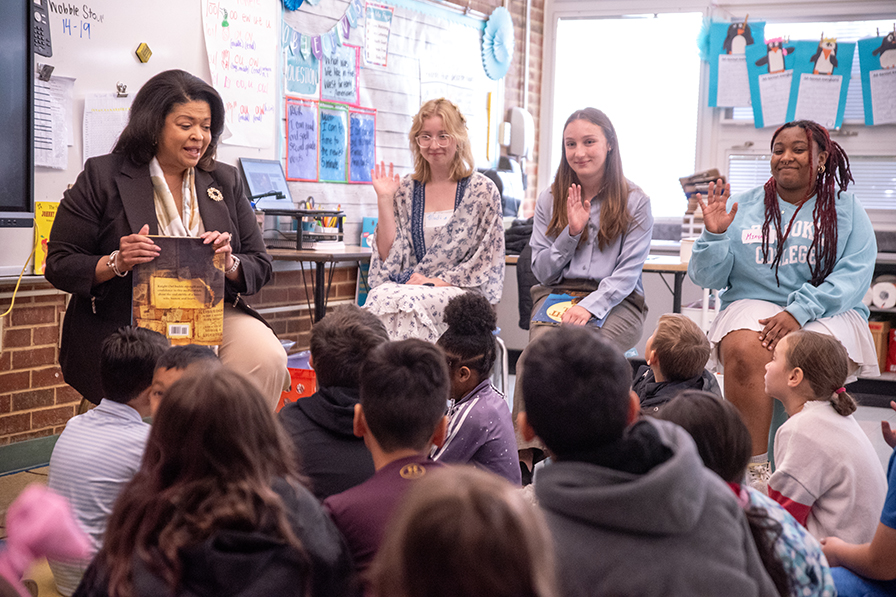 three students in a classroom with kids