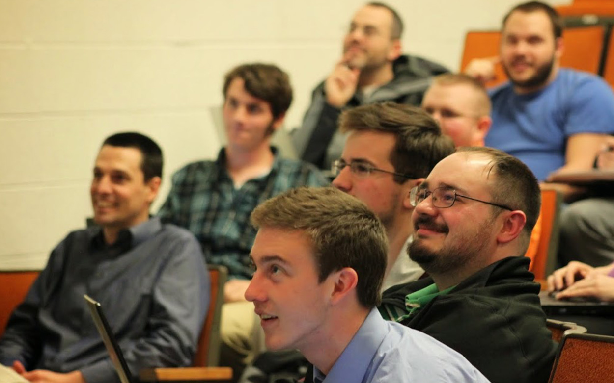 Students smile while watching math professors put on a magic show