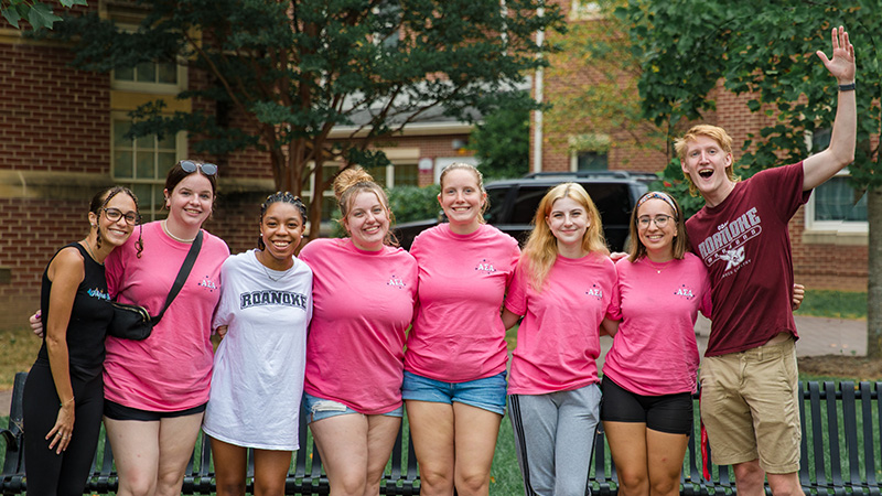 A group of students smiling on campus during move-in weekend.