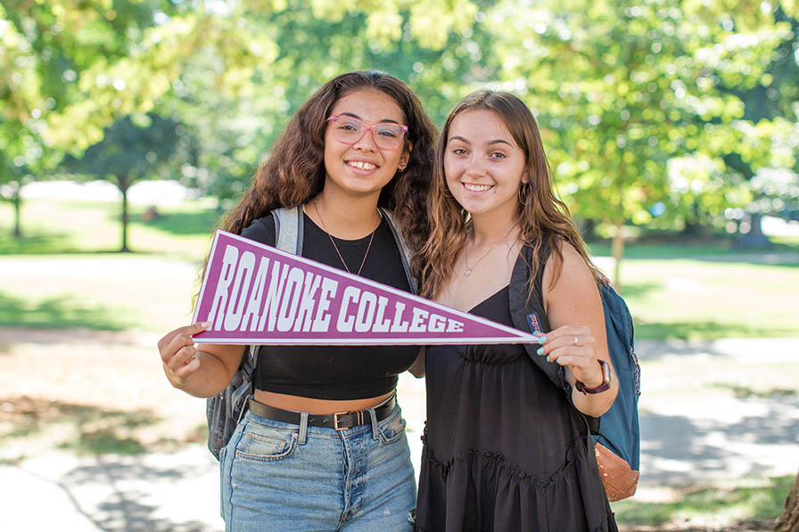 Two students holding Roanoke College pennant