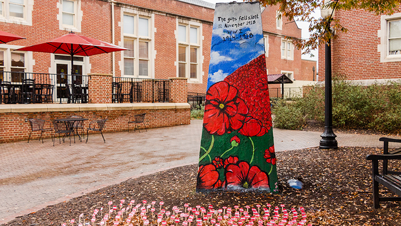 Rock painted with poppies and flags in the ground