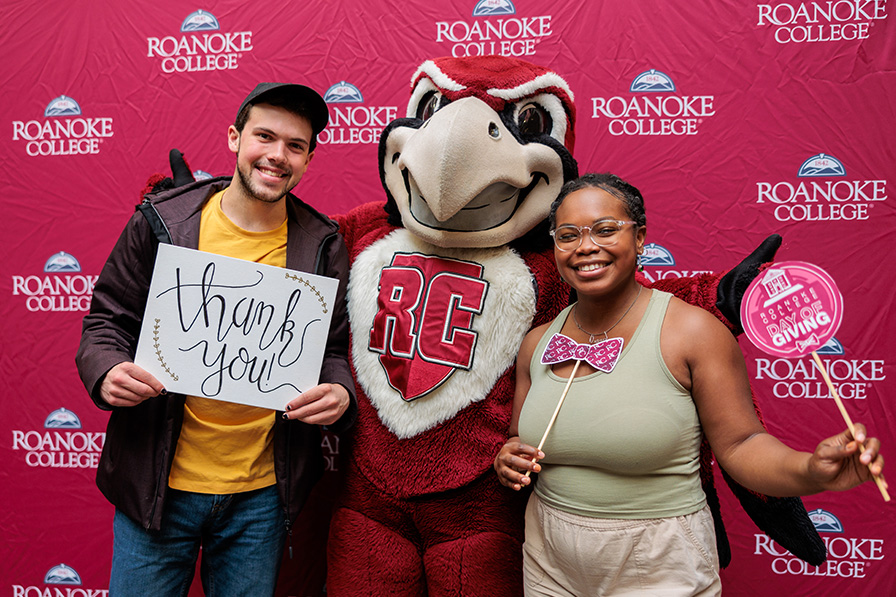 Students holding thank you signs with Roanoke's mascot, Rooney the bird