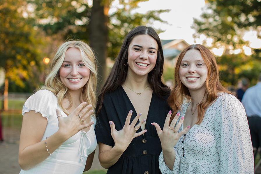 Three students wearing their class rings