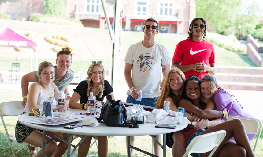 A group of people sitting and standing around a table