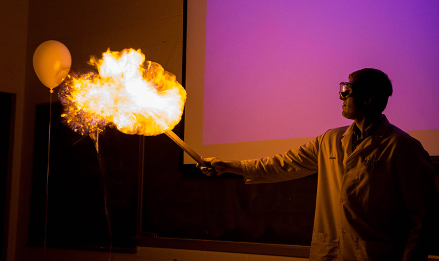 Male holding fire from a stick in Chemistry class