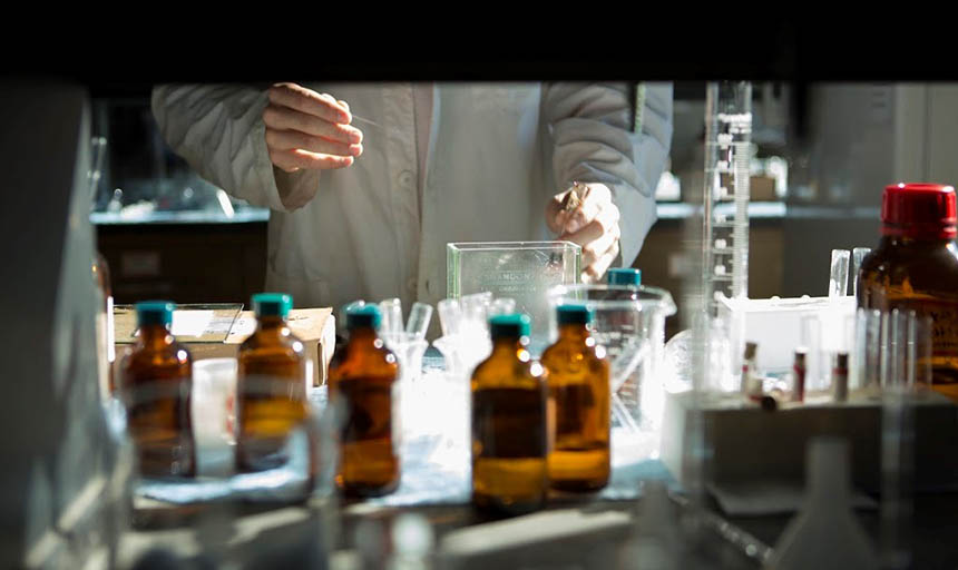 A photo from under a shelf showing hands working with chemicals