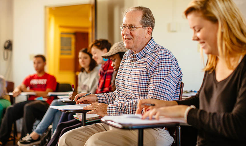 A professor sitting with his class and leading a discussion