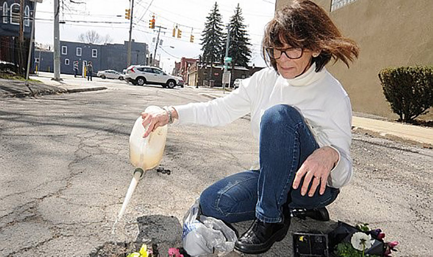 lady watering a plant in the street