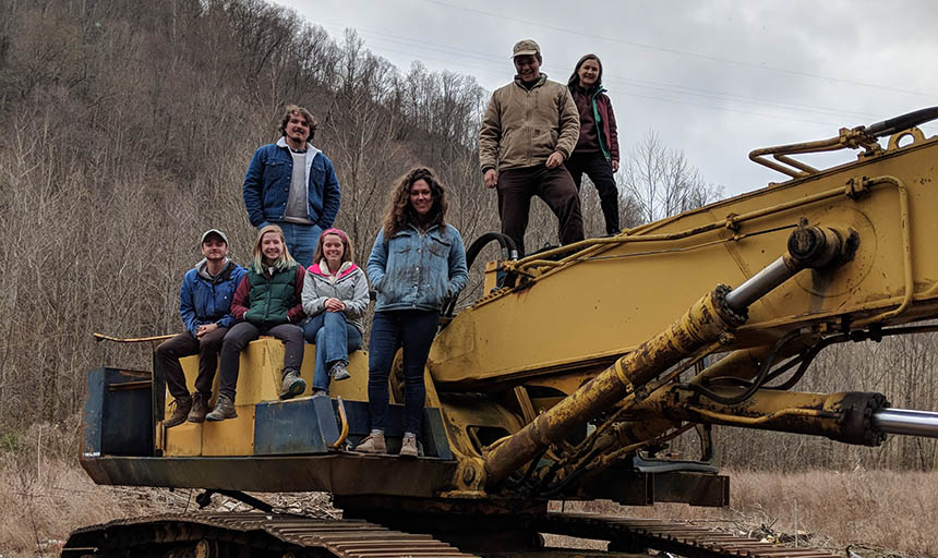 Students standing and sitting on a construction vehicle