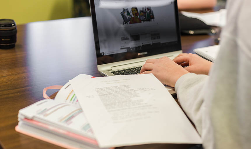 A student working on her laptop with her planner out