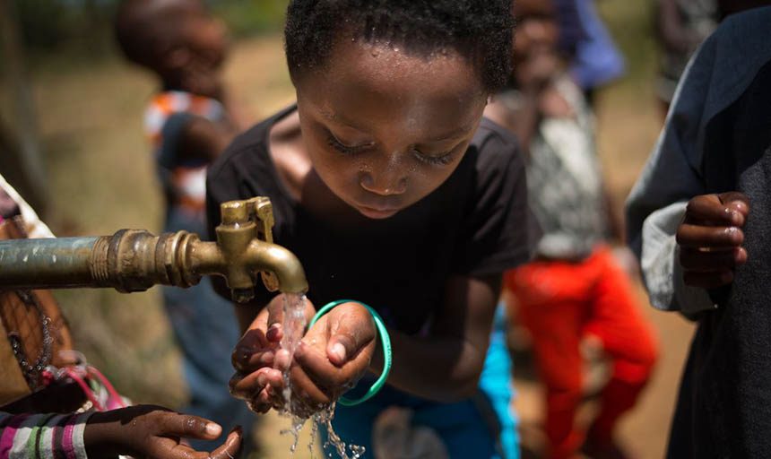 A child putting their hands under running water from a faucet