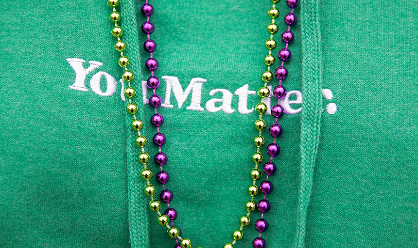 A green shirt that says "You Matter." The words are partially obscured by a string of purple and a string of gold beads