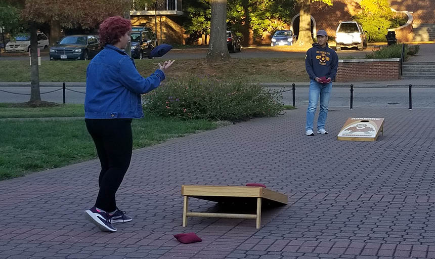 Students playing cornhole outside