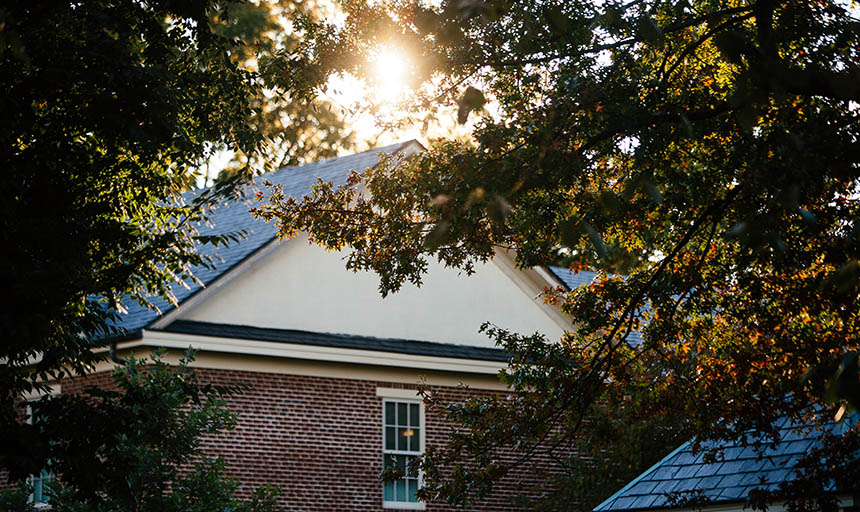 A partial view of the roof of trout hall through the trees