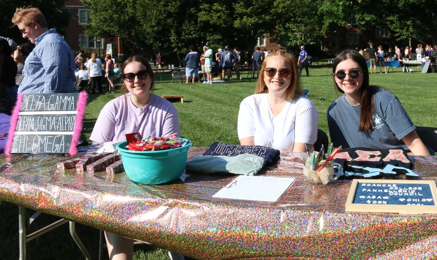 Students sitting at a table advertising one of the sororities at a campus activities fair