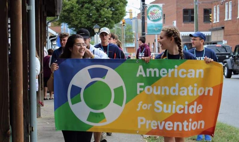 People walking and holding a banner that says "American Foundation for Suicide Prevention"