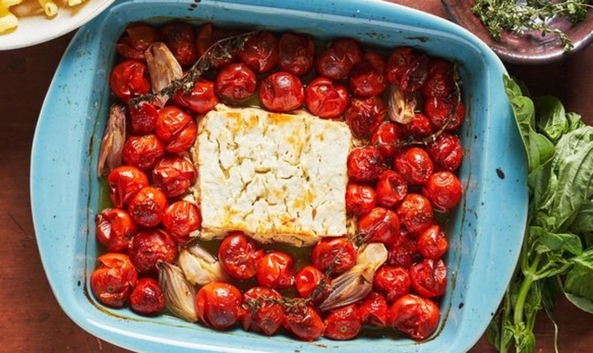 A photo of tomatoes and baked feta in a teal serving dish