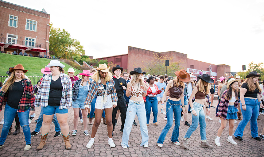 students wearing cowboy hats line dancing