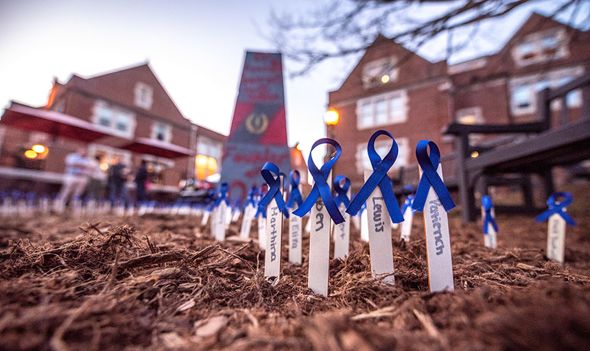 memorial blue ribbons staked into the ground with the college rock in the background