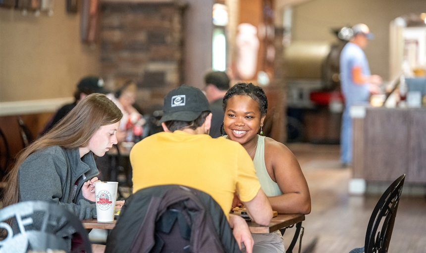 three students sitting in a coffee shop talking