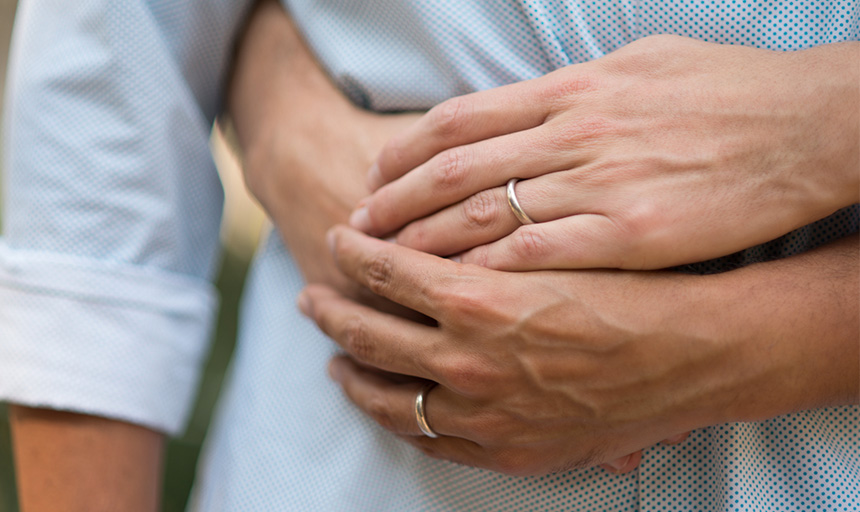 Two hands with wedding rings clasped together