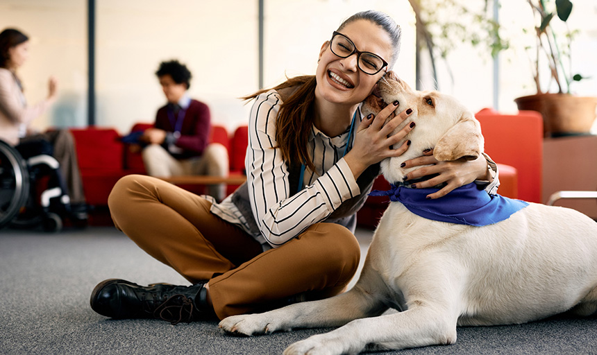 Woman smiles while being greeted by a therapy dog