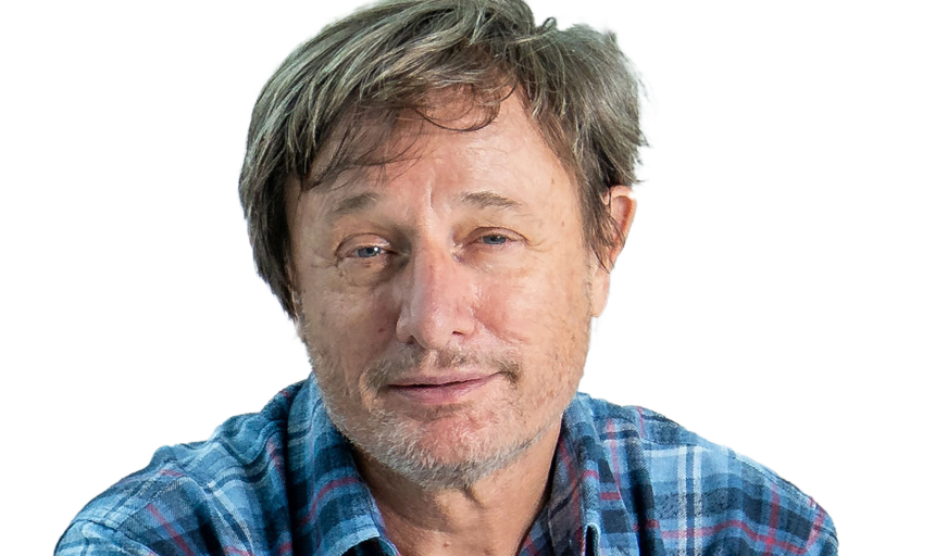 Headshot photo of man wearing a plaid blue shirt smiling at the camera.