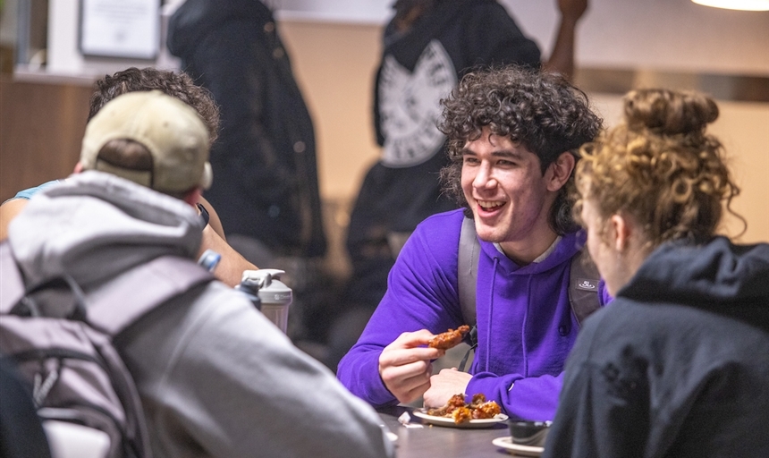 three people sitting at a table eating wings