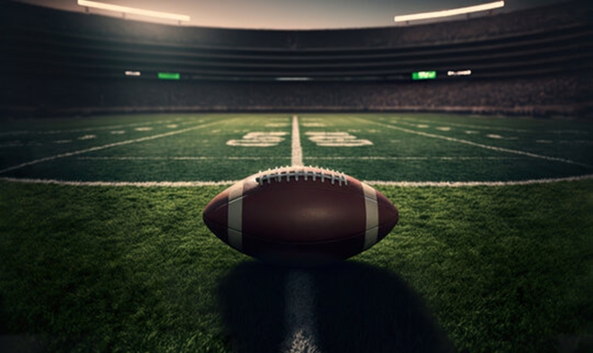 Dark photo of a football on the 50-yard line