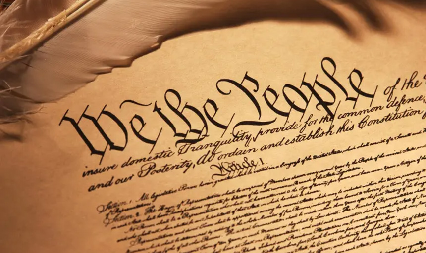 Yellowed page of the Constitution with "We the People" at the top in cursive